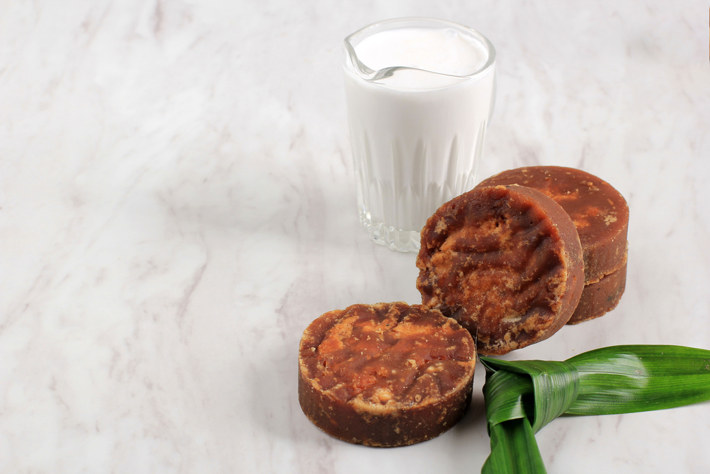 Gula Malacca or Coconut Palm Sugar, Popular as Brown Sugar (Gula Merah) with Coconut Milk and Pandan Leaf, Ingredients Aromatic Making Indonesian or Malaysian Traditional Cake. Isolated on White Marble Background